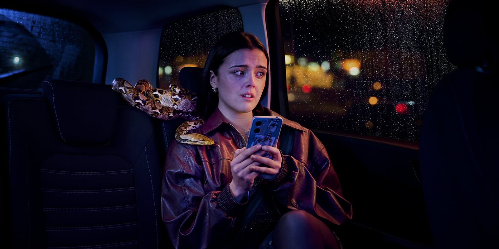 woman sitting in a taxi with a snake wrapped around her