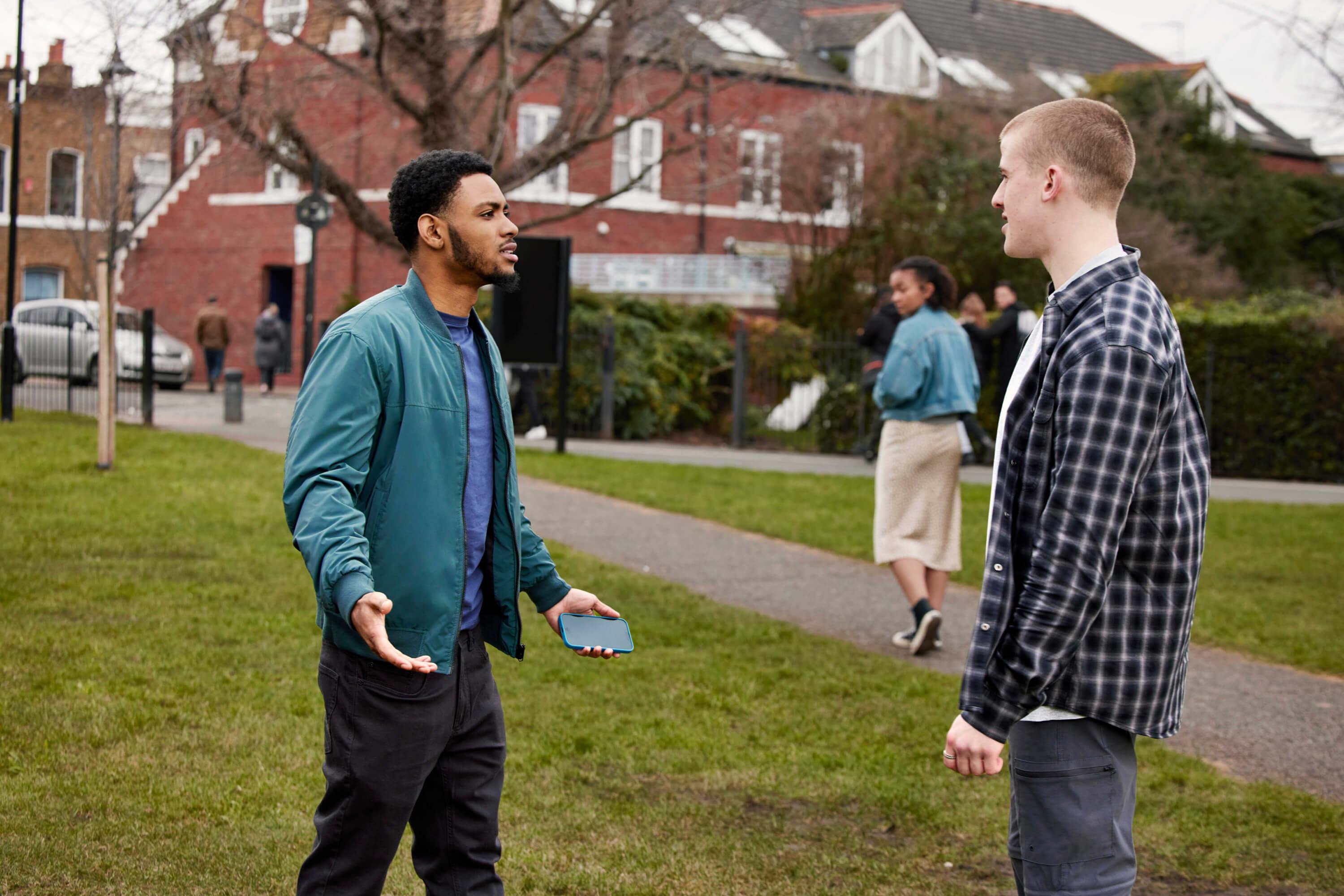 Banner image A man is stepping in to challenge another man who has used inappropriate language to a woman outside in a suburban environment. The woman is looking back towards the men as she walks away from the scene.