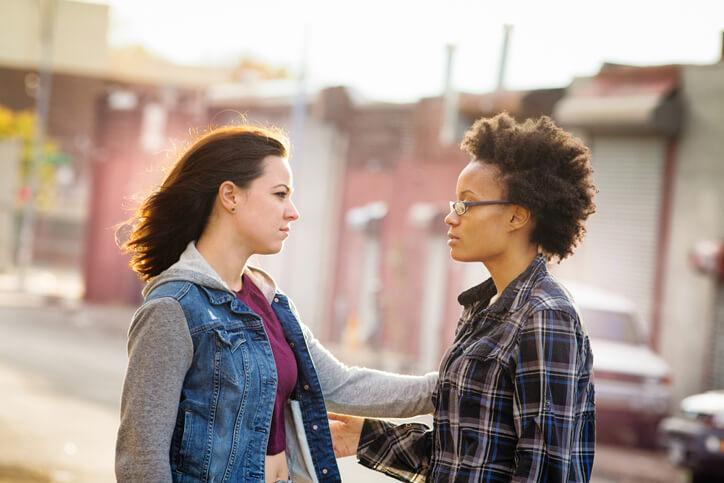 Banner image In a street, a young woman is checking to see if another woman is ok.