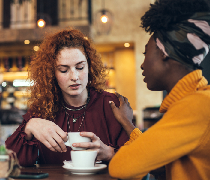 Two women in a coffee shop, speaking to each other