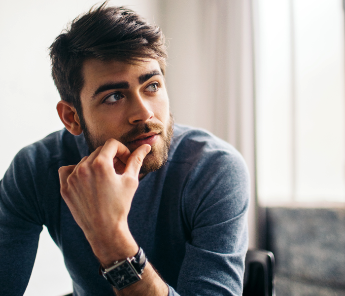 A man is holding his hands to his face, contemplating his behaviour