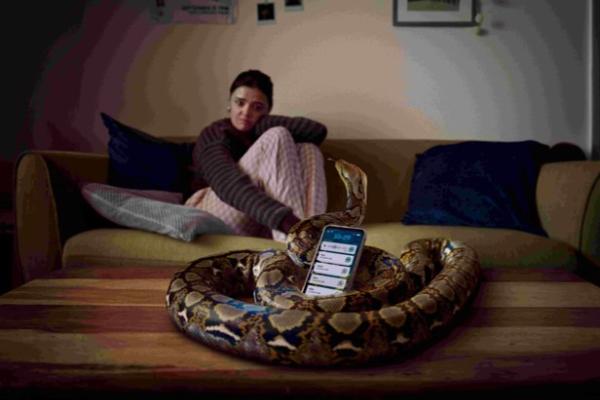 woman on couch with snake wrapped around her phone