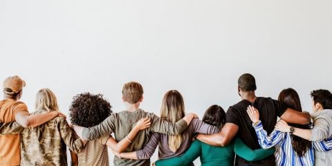 Group of people with linked arms, backs to camera.